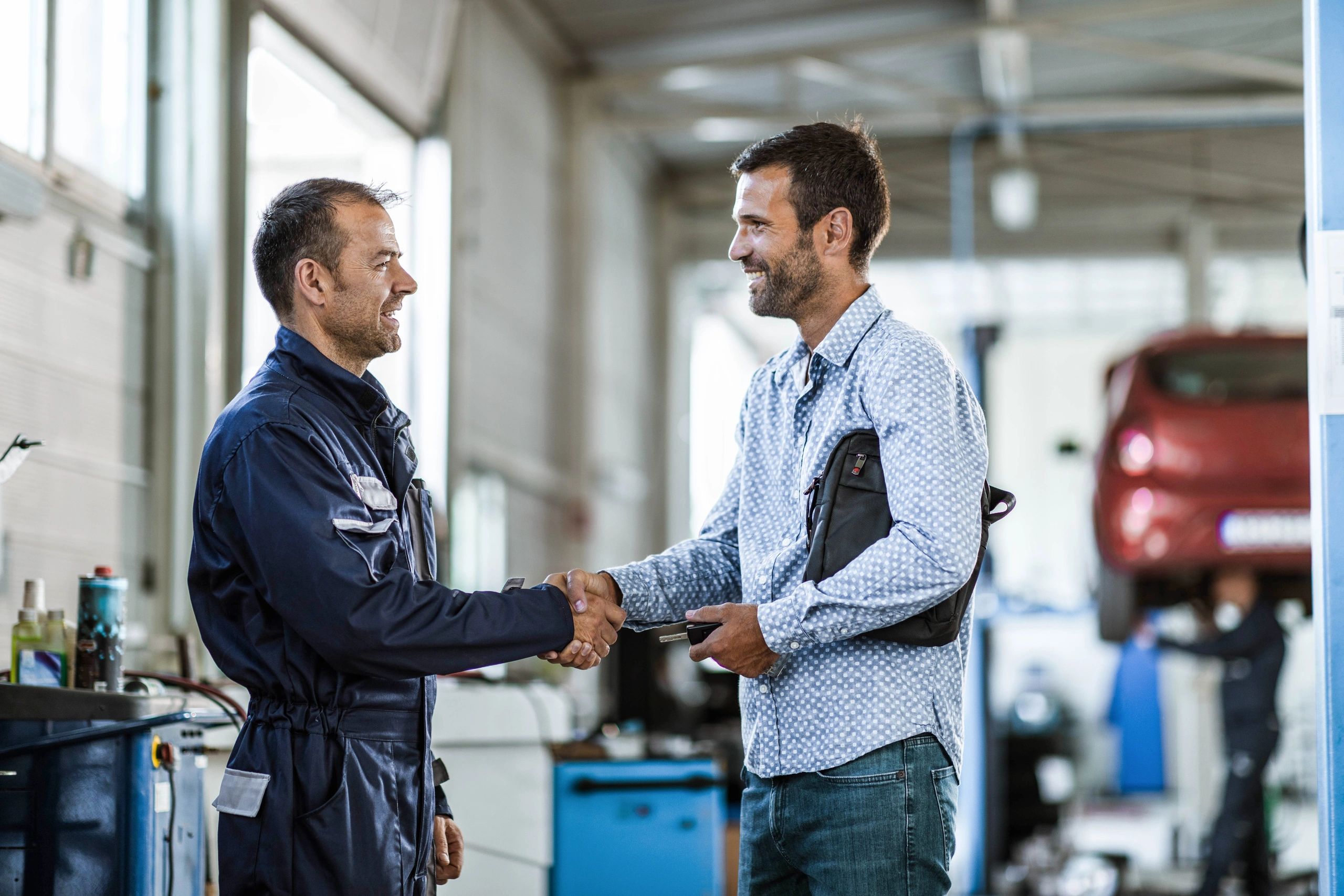 Customer shaking hands with a mechanic at an auto repair shop