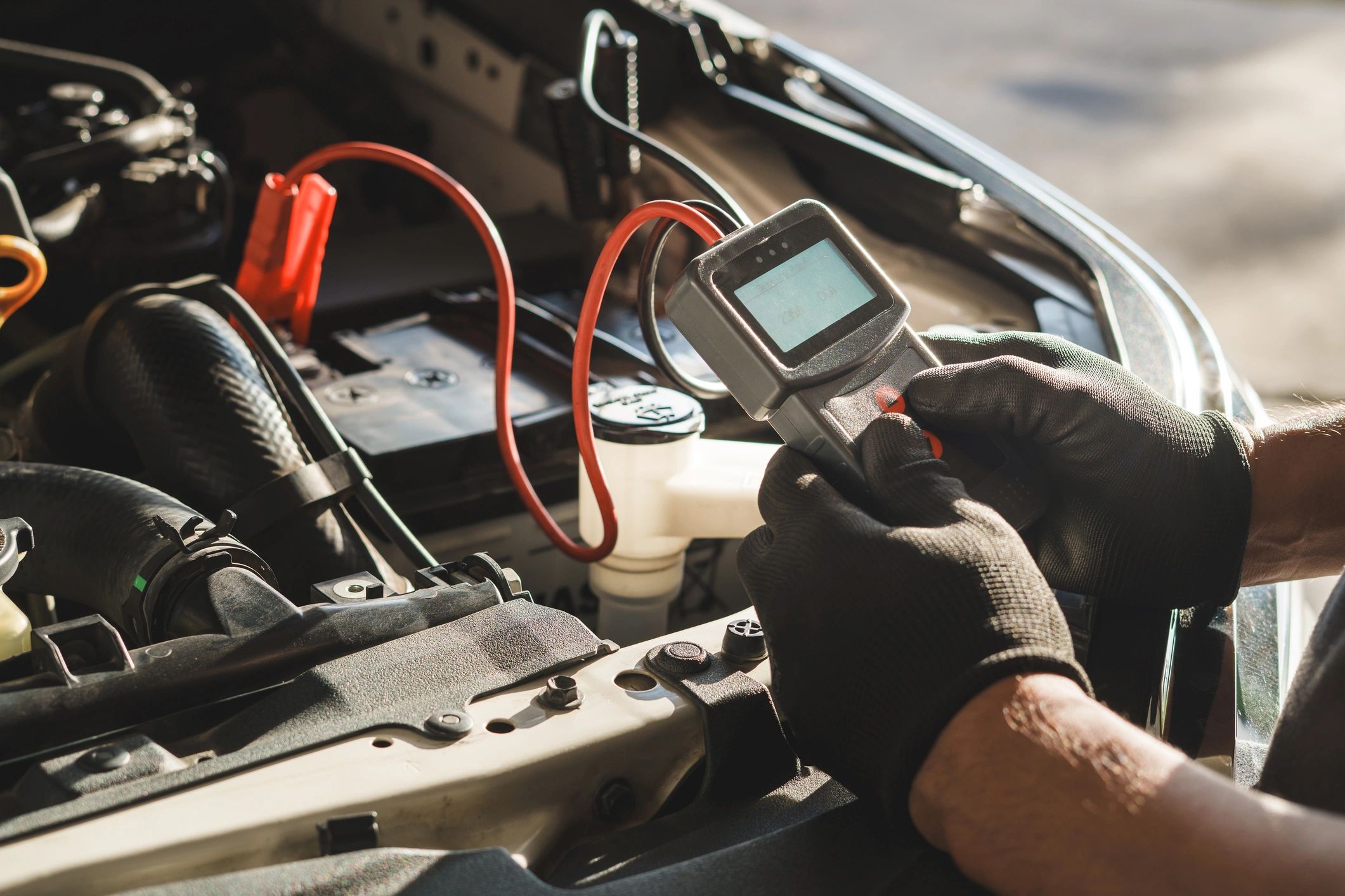 Technician using a diagnostic tool under the hood of a car